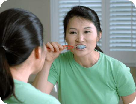 Woman brushing teeth with mirror reflection